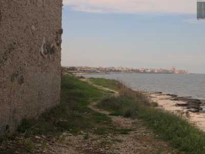 A questo punto imbocchiamo sulla sinistra uno stretto sentiero che ci permette di camminare a un metro dal mare avendo di fronte a noi lo skyline del centro storico di Giovinazzo